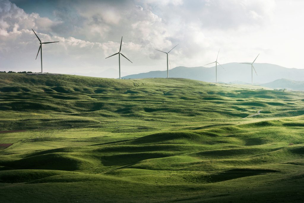 Parque eólico en un valle verde, rodeado de majestuosas montañas, simbolizando la transición energética justa hacia fuentes renovables y sostenibles